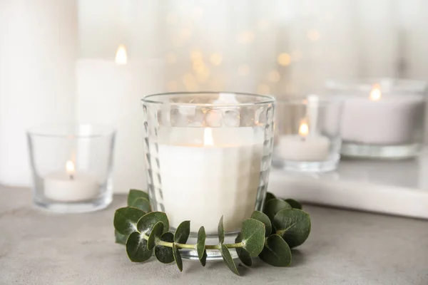 Burning aromatic candle and eucalyptus branch on table — Stock Photo, Image