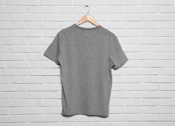 Hanger with blank t-shirt on white brick wall. Mock up for design — Stock Photo, Image