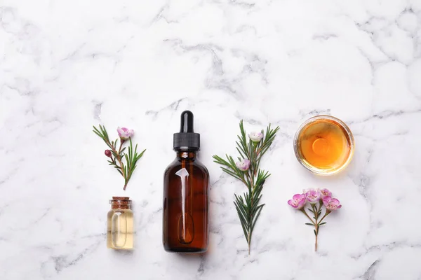 Composição de leigos planos com garrafas de óleo de árvore de chá natural na mesa de mármore — Fotografia de Stock