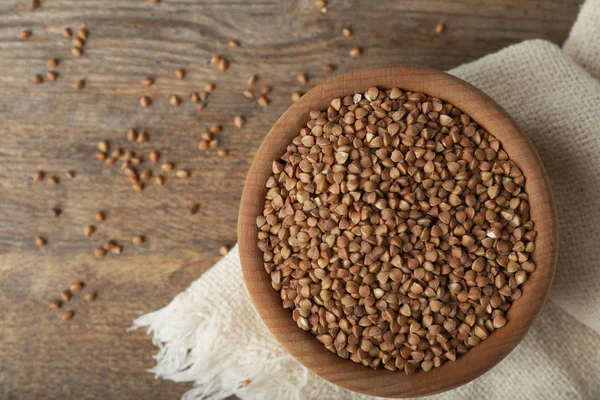 Buchweizen ungekocht in Schüssel auf Holztisch, flach gelegt. Raum für Text — Stockfoto