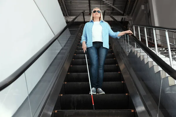 Persona ciega con bastón largo en escaleras mecánicas en interiores — Foto de Stock