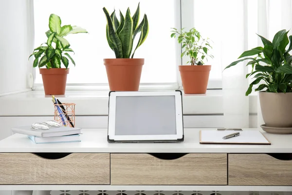 Tableta sobre mesa y plantas de interior de oficina, espacio para texto —  Fotos de Stock