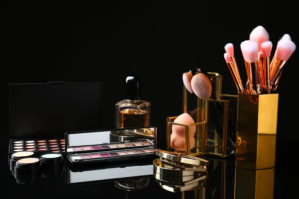 Set of makeup products and brushes on dark background — Stock Photo, Image
