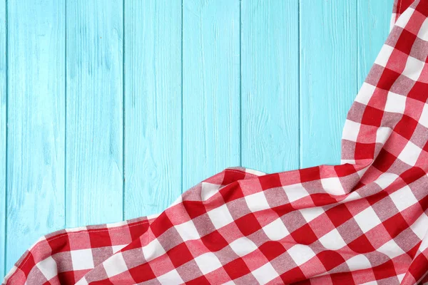 Checkered picnic blanket on wooden background top view. Space for