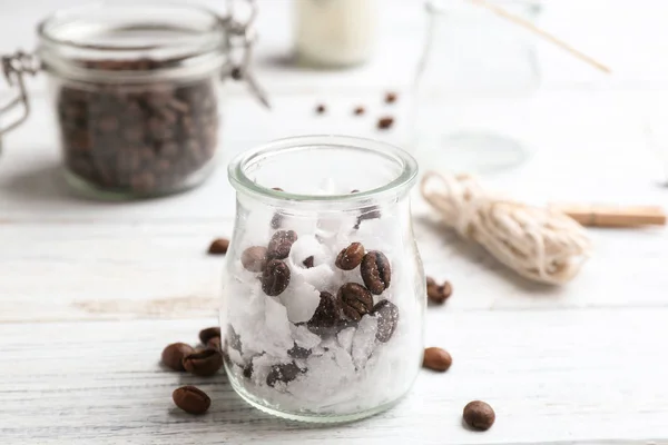 Pot en verre, cire et grains de café pour la fabrication de bougies faites à la main sur une table en bois — Photo