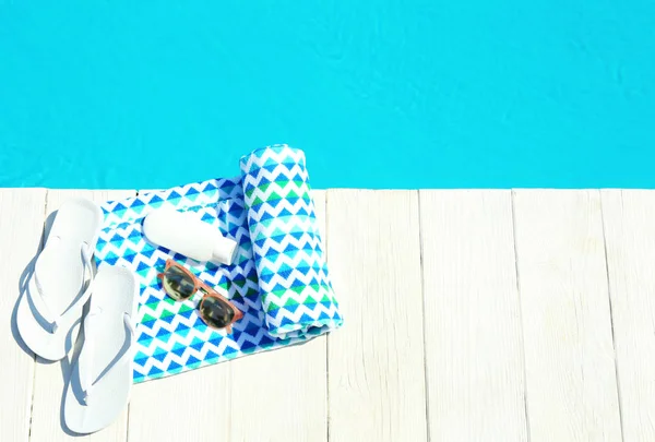 Accesorios de playa en la cubierta de madera cerca de la piscina, vista superior. Espacio para texto —  Fotos de Stock