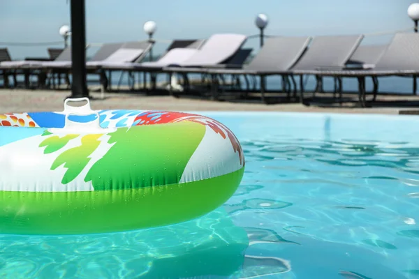 Anillo inflable colorido flotando en la piscina en el día soleado, al aire libre. Espacio para texto — Foto de Stock