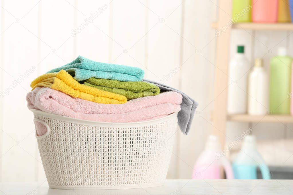 Basket with clean laundry on table at home, space for text
