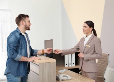 Modern otelde resepsiyonda müşteriile çalışan profesyonel resepsiyonist