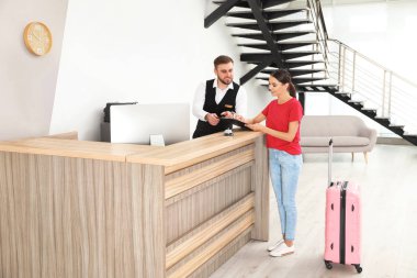 Modern otelde resepsiyonda müşteriile çalışan profesyonel resepsiyonist