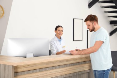 Modern klinikte hasta ile çalışan profesyonel resepsiyonist