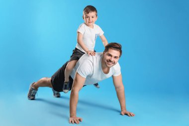 Baba renkli arka plan karşı sırtında oğlu ile şınav yapıyor