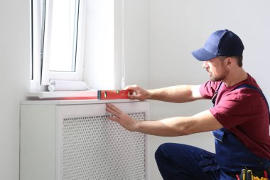 Handyman üniformalı bina seviyesi kapalı çalışma. Profesyonel inşaat araçları