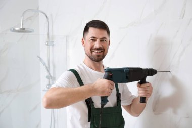 Handyman banyoda matkapla çalışıyor. Profesyonel inşaat araçları