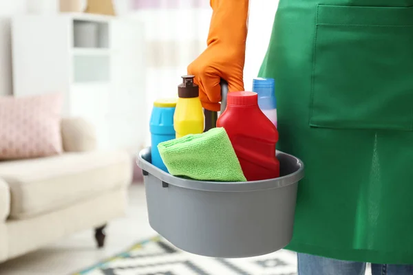 Mulher com bacia de detergentes na sala de estar, close up. Serviço de limpeza — Fotografia de Stock