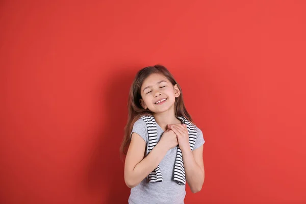 Retrato de una chica cogida de la mano cerca de su corazón sobre fondo de color —  Fotos de Stock