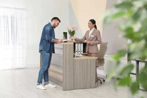 Professionele receptioniste werken met klant bij Bureau in modern hotel — Stockfoto