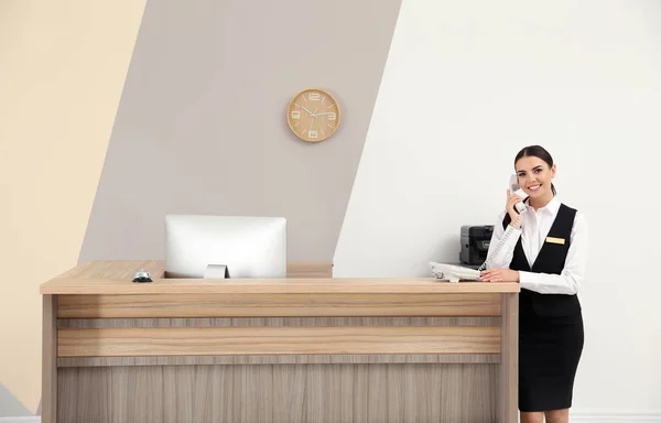Recepcionista falando por telefone perto de mesa no hotel moderno — Fotografia de Stock