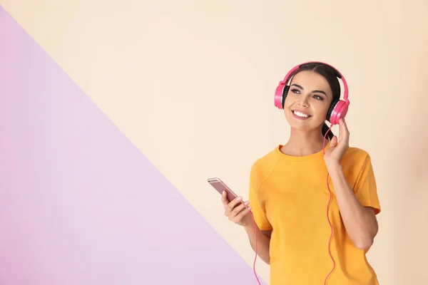 Ελκυστική γυναίκα με κινητό τηλέφωνο απολαμβάνοντας μουσική στα ακουστικά στο φόντο χρώμα. Χώρος για κείμενο — Φωτογραφία Αρχείου