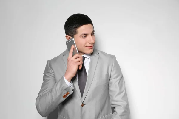 Retrato de jovem empresário falando ao telefone contra fundo claro — Fotografia de Stock