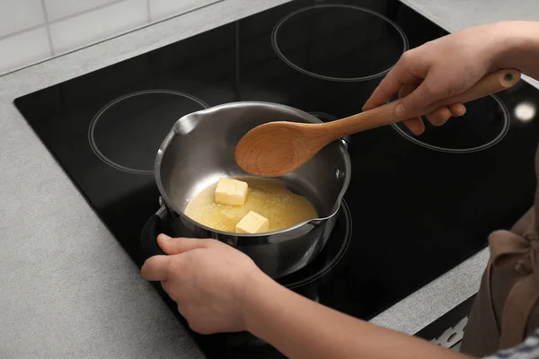 Woman stirring butter in saucepan on electric stove, closeup — Stock Photo, Image