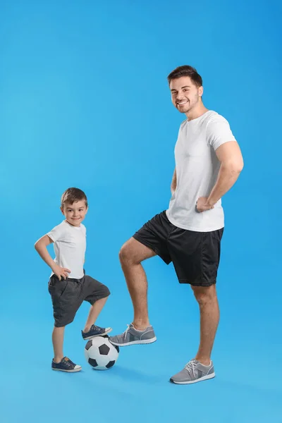 Ritratto di papà e suo figlio con pallone da calcio su sfondo a colori — Foto Stock