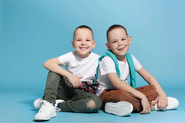 Pełna długość Portret cute braci bliźniak siedzi na tle koloru — Zdjęcie stockowe