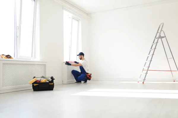 Handyman en uniforme trabajando con el nivel del edificio en interiores, espacio para el texto. Herramientas de construcción profesionales — Foto de Stock