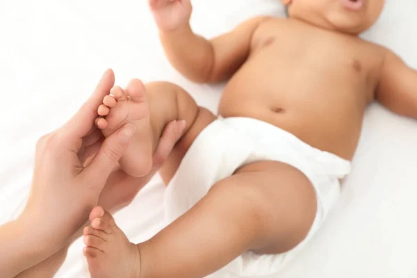 Mamma och hennes söta barn på vita sängen, närbild. Baby massage och övningar — Stockfoto