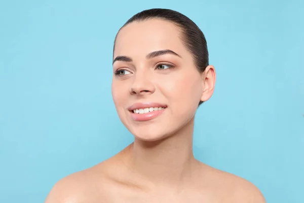 Retrato de mujer joven con rostro hermoso y maquillaje natural sobre fondo de color — Foto de Stock