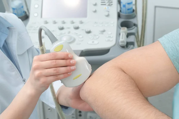 Doktor dirigování ultrazvukového vyšetření pacientova lokte na klinice, zaostřená — Stock fotografie