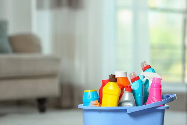Plastikowe wiadro z różnymi produktami czyszczącym w pomieszczeniu, miejsce na tekst — Zdjęcie stockowe