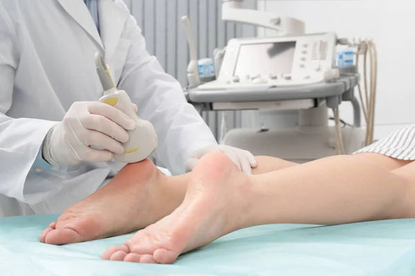 Doctor conducting ultrasound examination of patient\'s foot in clinic, closeup
