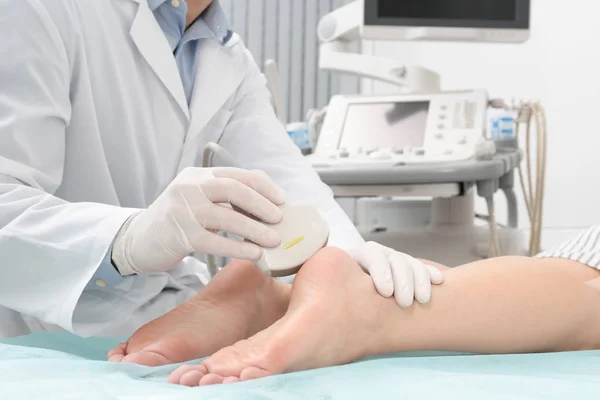 Doctor conducting ultrasound examination of patient\'s foot in clinic, closeup