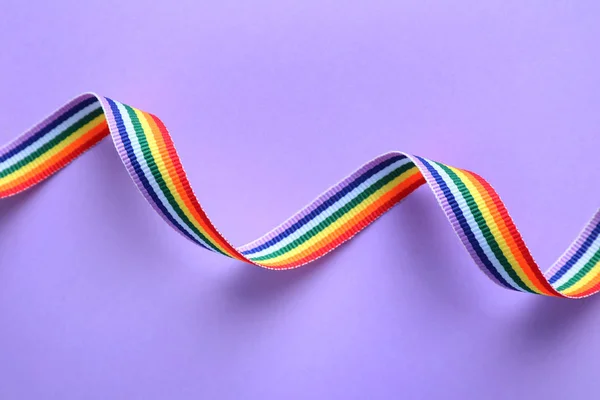 Bright rainbow ribbon on color background, top view. Symbol of gay community