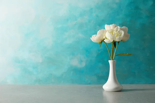 Peonías fragantes en jarrón sobre tabla sobre fondo de color, espacio para texto. Hermosas flores de primavera — Foto de Stock