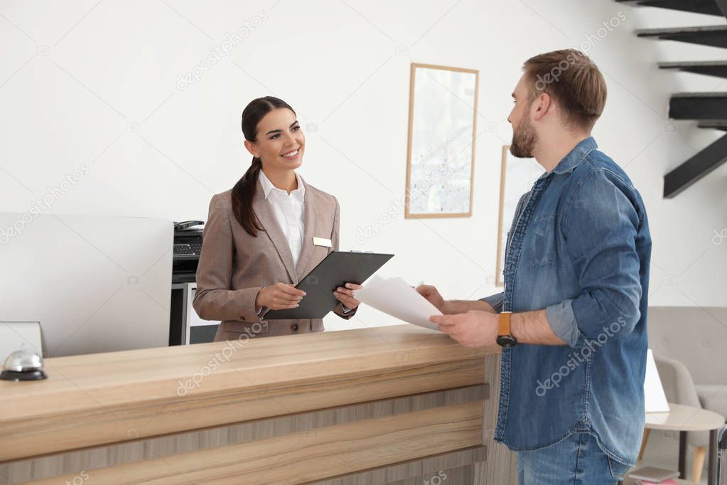 Professional receptionist working with client at desk in modern hotel