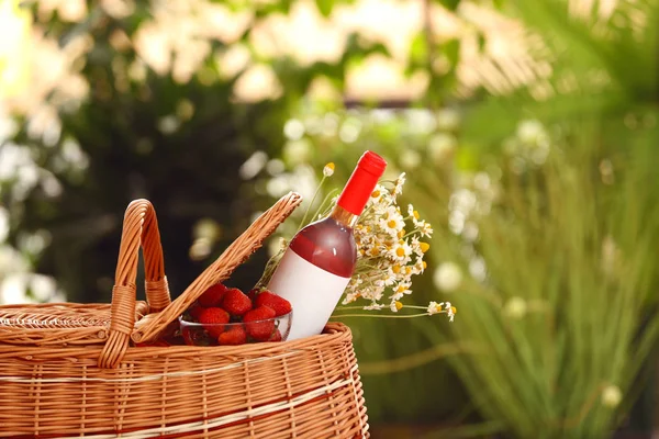 Корзина для пикника с вином, клубникой и цветами на размытом фоне, место для текста — стоковое фото