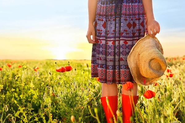 Wanita mengenakan sepatu bot merah di ladang opium pada malam hari, closeup. Ruang untuk teks — Stok Foto