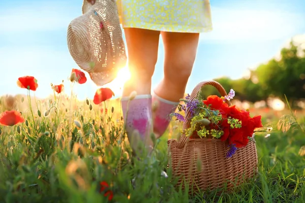 Жінка з кошиком маків і польовими квітами в сонячному світлі, крупним планом — стокове фото