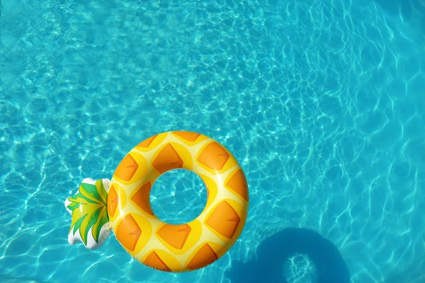 Яркое надувное ананасовое кольцо, плавающее в бассейне в солнечный день, над видом — стоковое фото
