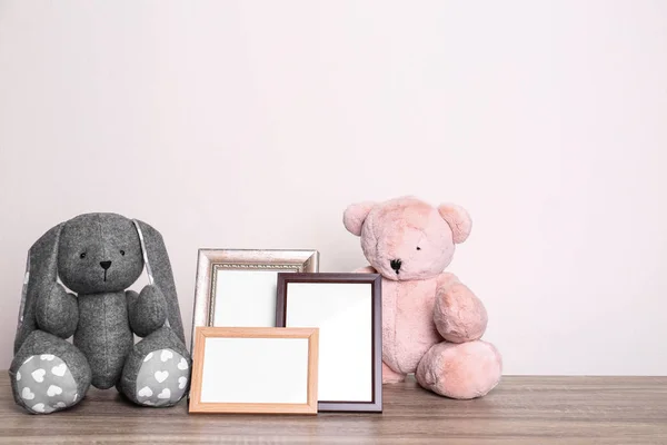 Cadres photo et adorables jouets sur la table sur fond clair, espace pour le texte. Éléments de chambre enfant — Photo