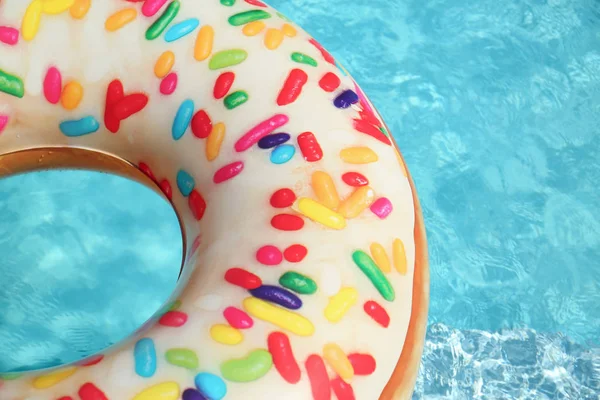 Anneau de beignet gonflable lumineux flottant dans la piscine le jour ensoleillé. Espace pour le texte — Photo