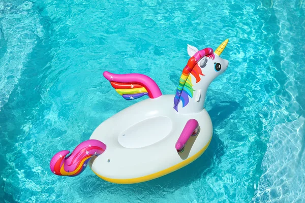 Funny inflatable unicorn ring floating in swimming pool on sunny day