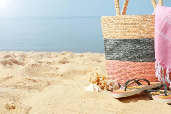 Bag and flip flops on sand, space for text. Beach accessories