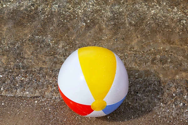 Jasna nadmuchiwana piłka plażowa na piaszczystej plaży w pobliżu morza — Zdjęcie stockowe