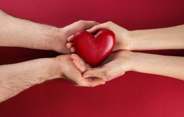 Renkli arka planda dekoratif kalp tutan çift, üst görünüm