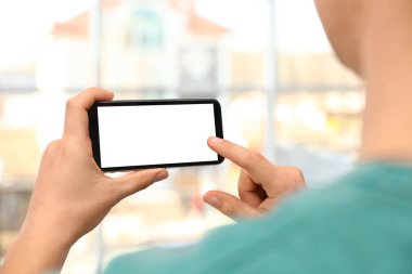 Bulanık arka planda boş ekrana sahip akıllı telefonu tutan adam, ellerin yakın çekim. Metin için alan