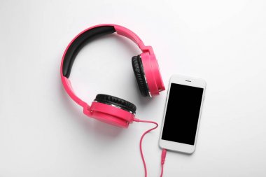 Şık kulaklıklar ve beyaz arka planda modern telefon, üst görünüm. Metin alanı