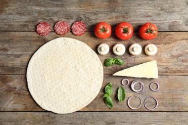 Ahşap masa üzerinde pizza için taban ve malzemeler ile Düz yatıyordu kompozisyon